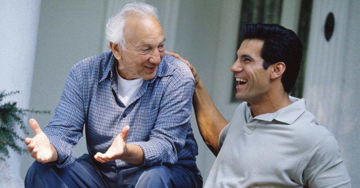 Health Benefits of Laughter. Picture of a Caucasian elderly man laughing with a younger Caucasian man.